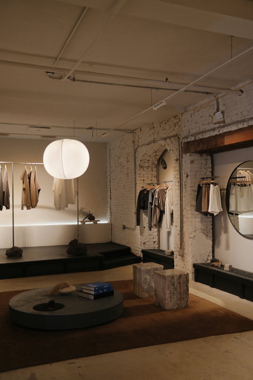 Minimalist clothing boutique featuring metal racks and stone seating.