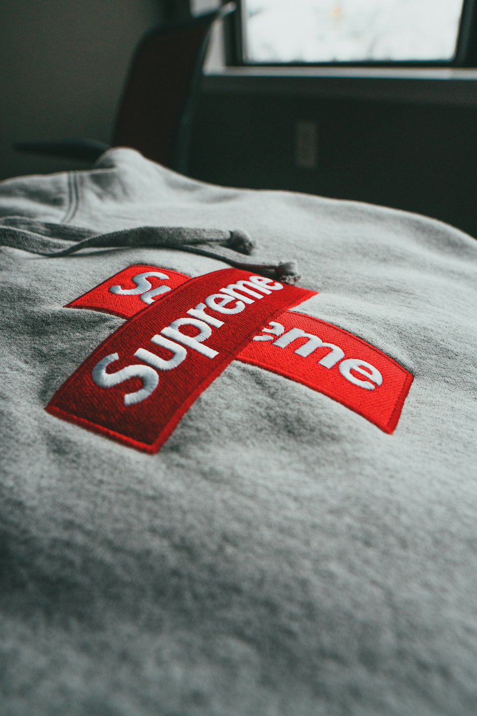 A grey hoodie with a red and white logo.